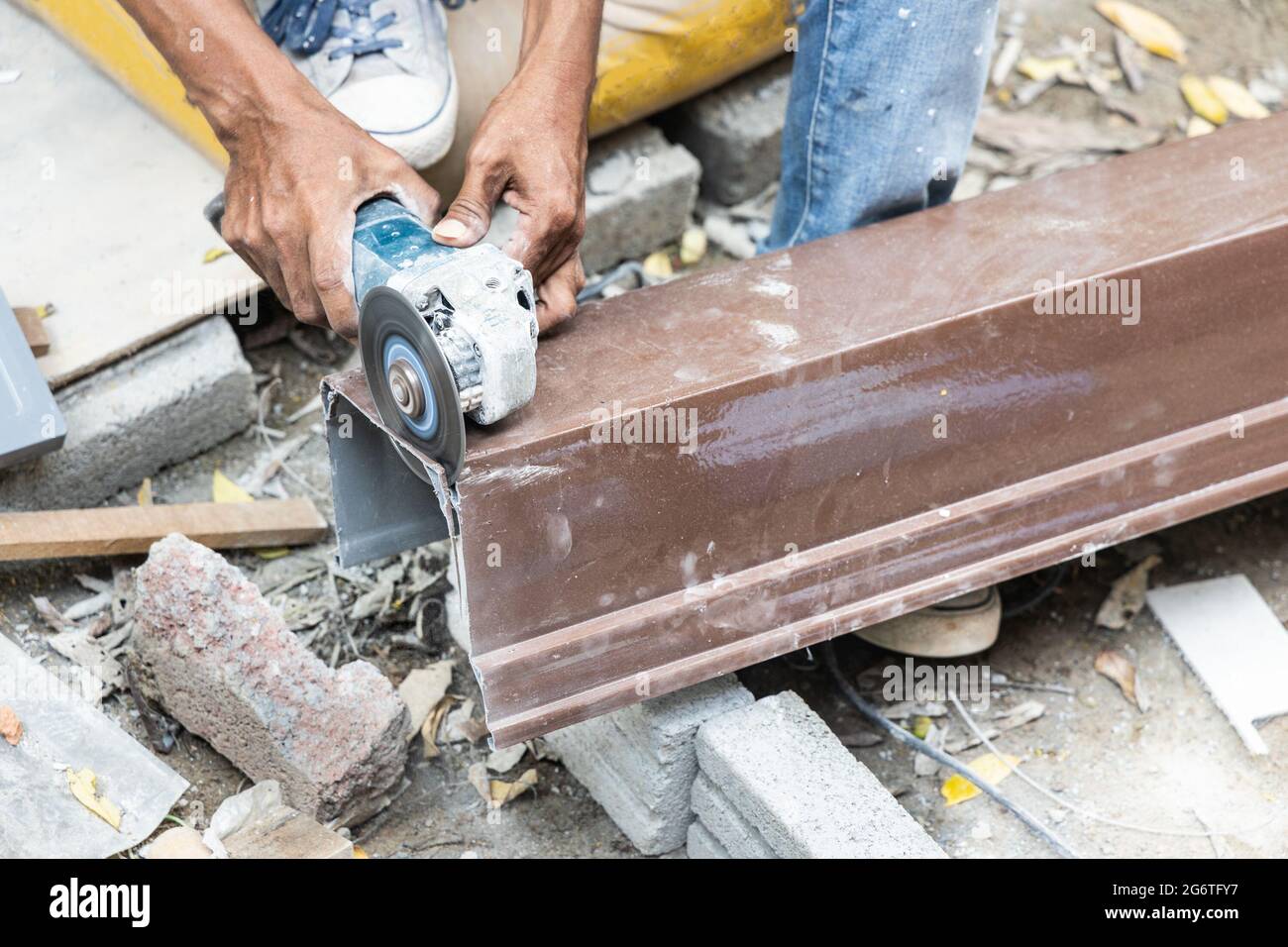 Arbeiter schneidet Wasserrinne mit Scheibenschneider Elektrowerkzeug Stockfoto