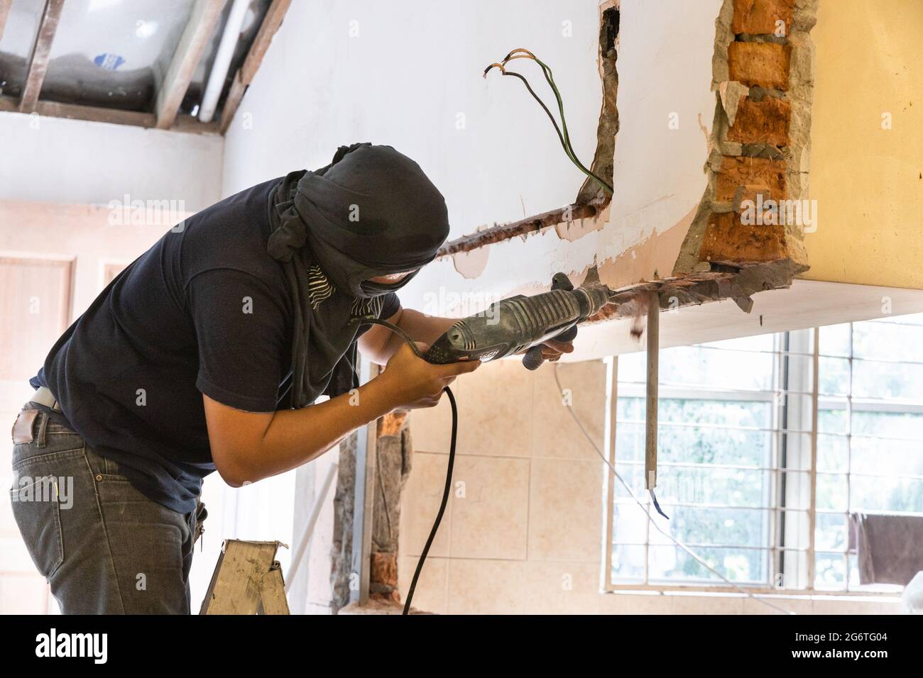Arbeiter bohren an der Wand, um Hohlraum für Stromkabel bei der Renovierung zu schaffen Stockfoto