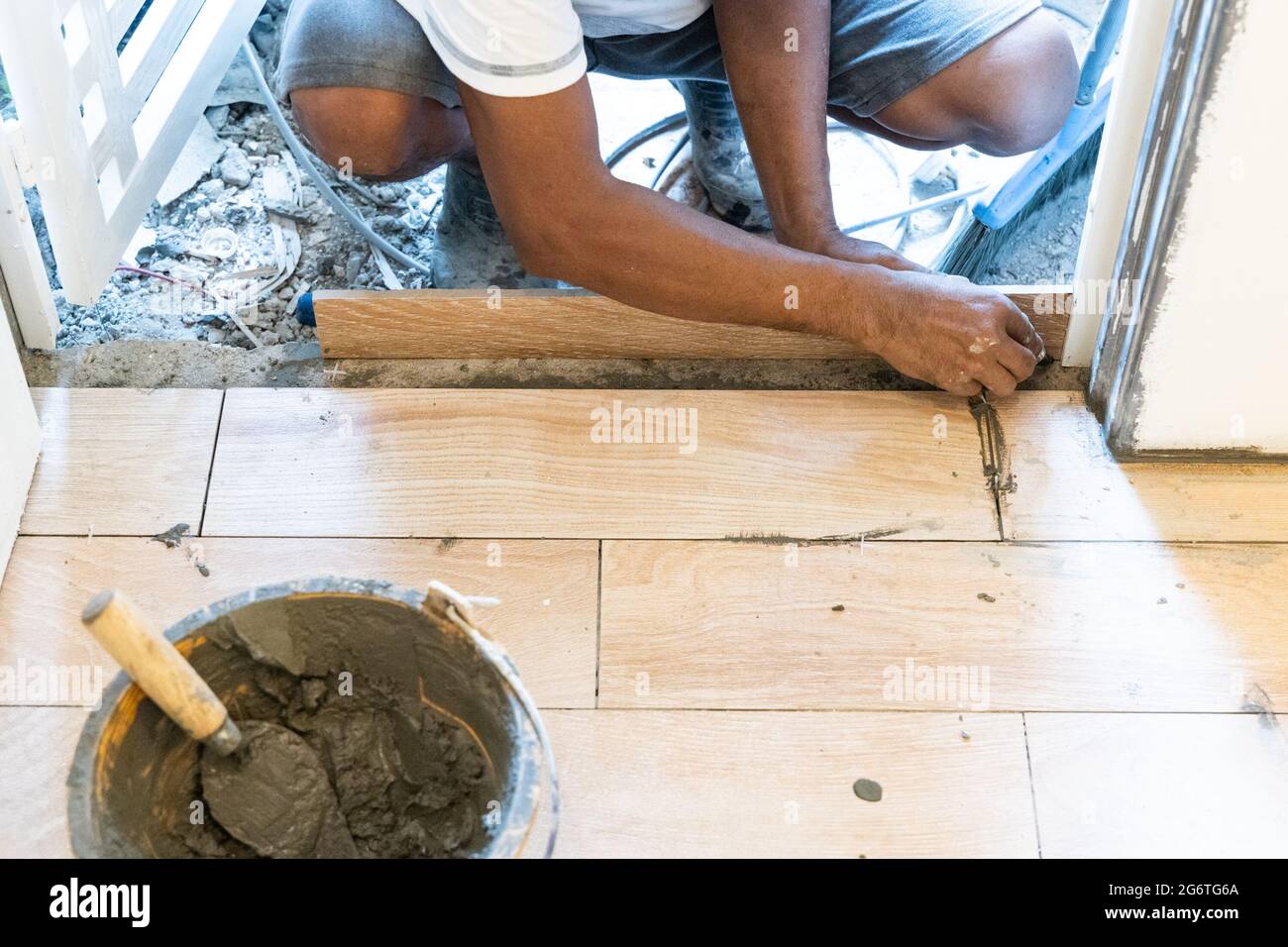 Arbeiter, der keramische Bodenfliesen an der Türkante installiert Stockfoto