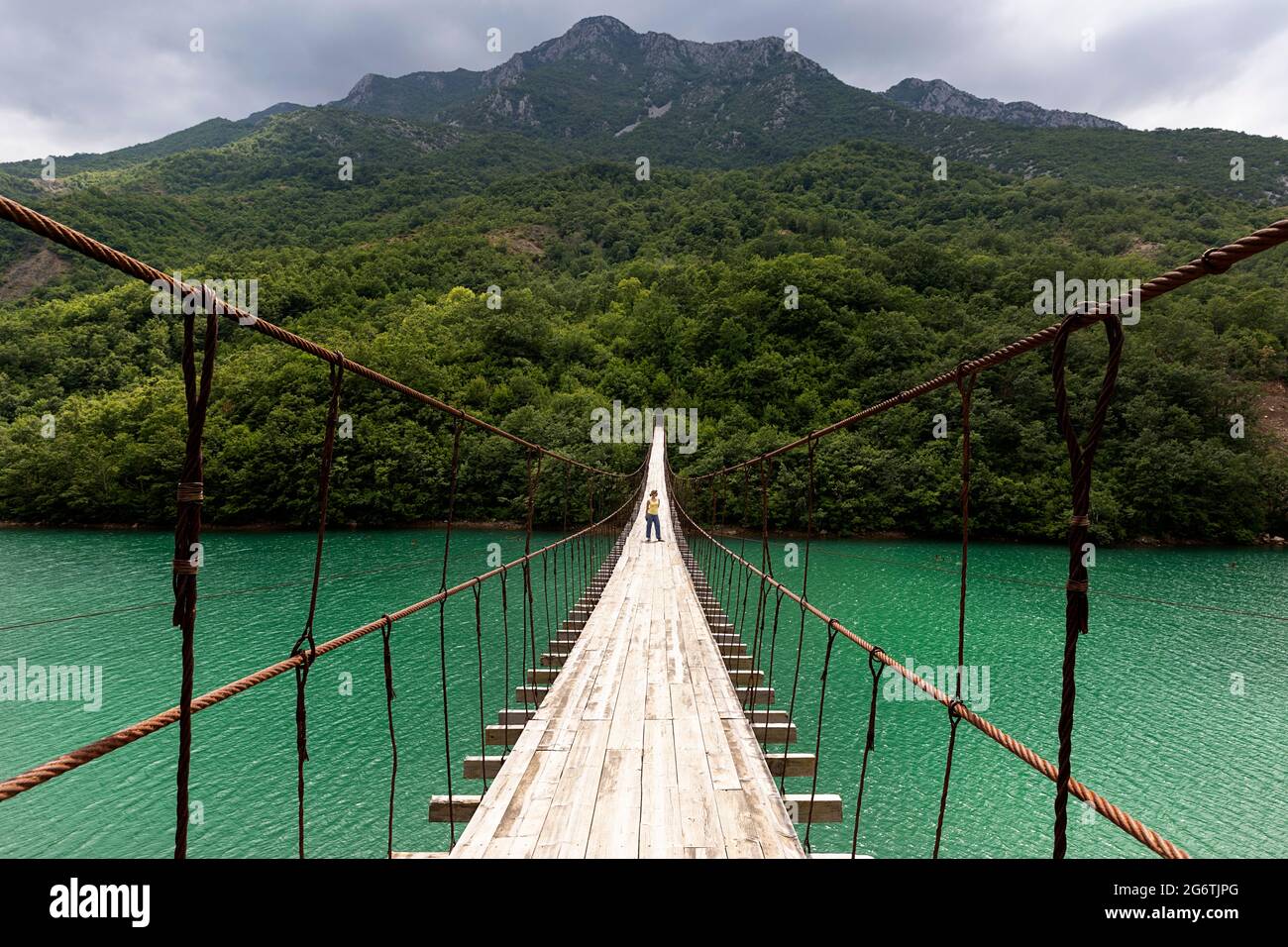 Frau, die auf einer Hängebrücke oder Hängebrücke über den wunderschönen smaragdgrünen Fluss, Albanien, läuft Stockfoto