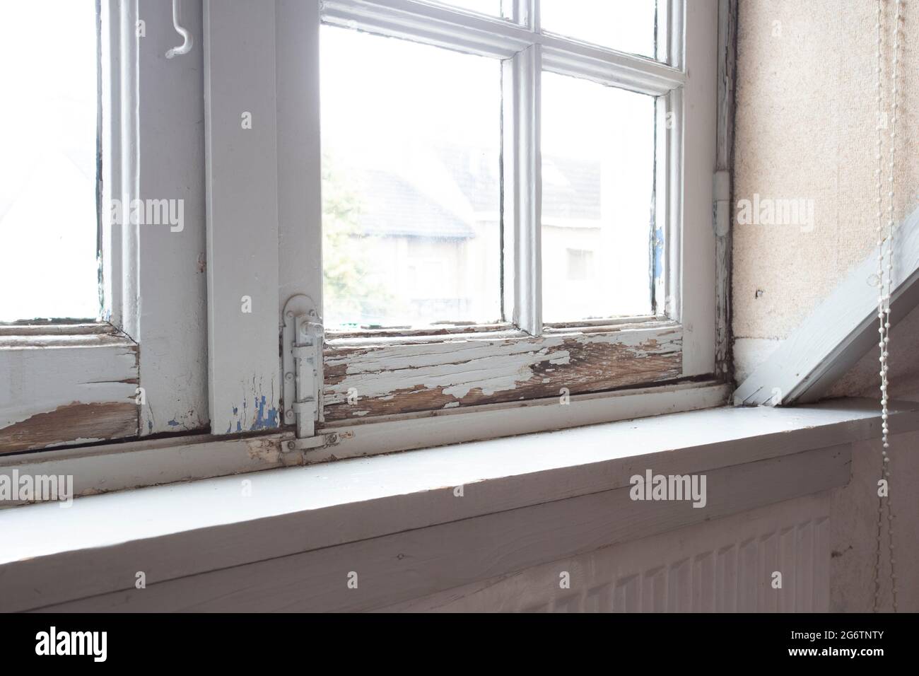 Alte Holzfensterrahmen mit verrottem Holz und rissiger abblätternder Farbe, das Haus muss renoviert werden und neue Rahmen Stockfoto