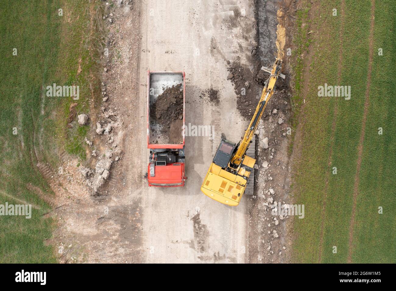 Bagger graben Boden in der Nähe des Feldes und Verladung auf den LKW Stockfoto