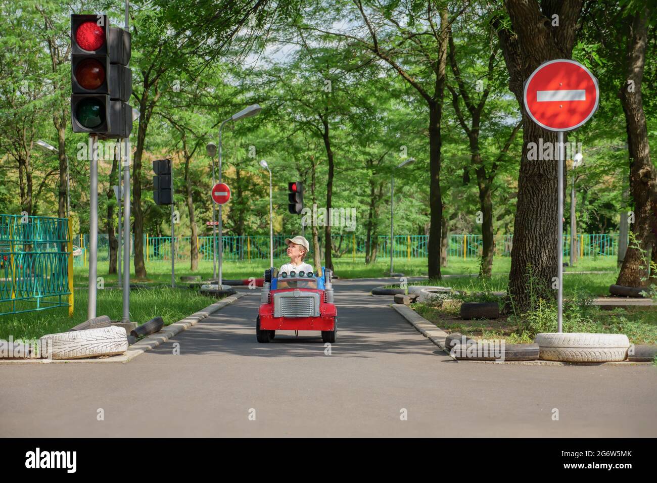 Sicherheitsspielplatz für den Straßenverkehr. Kleiner Junge fährt Spielzeugauto hält an der Ampel auf Spielplatz Kind lernen Verkehrsregeln Spiel Straßenverkehrssicherheit Ausbildung Stockfoto