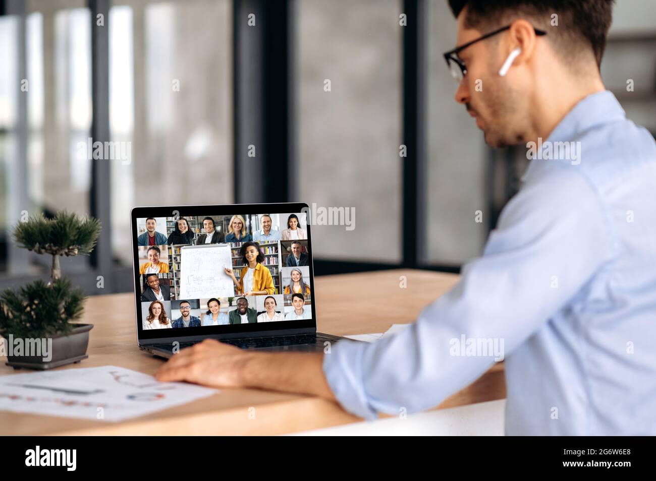E-Learning-Konzept. Kaukasischer moderner Typ, studiert fernab, hört sich eine Online-Vorlesung an, Lehrerin führt eine Lektion durch, multinationale Studenten unterschiedlichen Alters erwerben Wissen Stockfoto