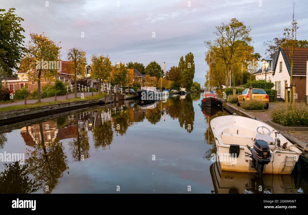 Geeuw Kanal mit Booten und Häusern in goldener Stunde, Stadt IJlst, Friesland, Niederlande Stockfoto