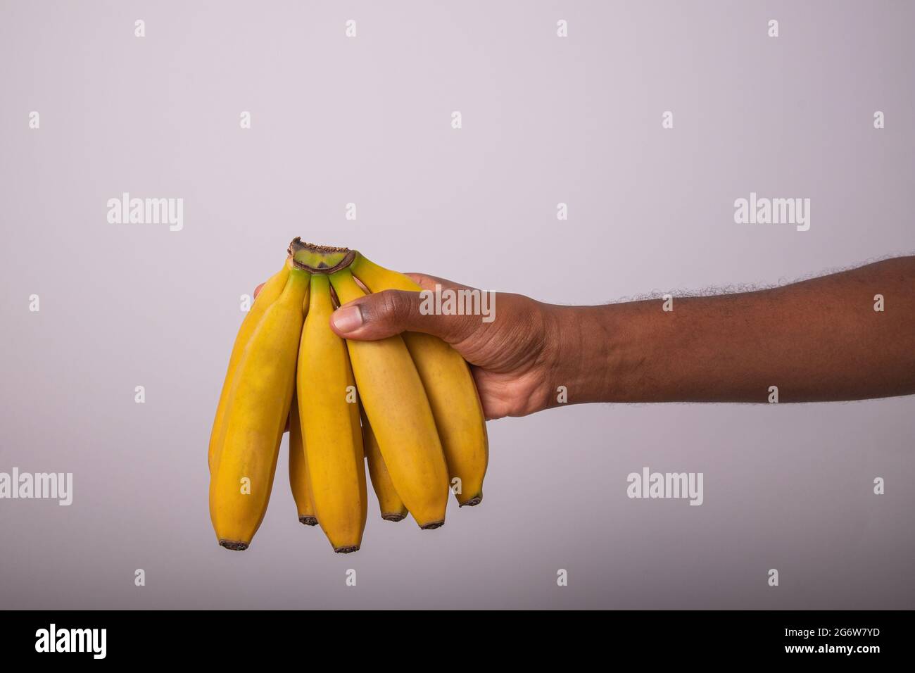Ein Haufen Bananen, die von einem Mann gehalten werden. Appetitliche Bananen auf weißem Hintergrund isoliert. Stockfoto