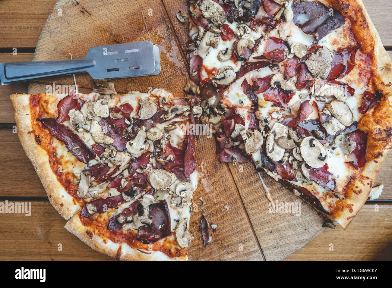 Nahaufnahme einer in Scheiben geschnittenen gebackenen Pizza auf dem Tisch zu Hause oder im Restaurant auf dem Brett Draufsicht Stockfoto