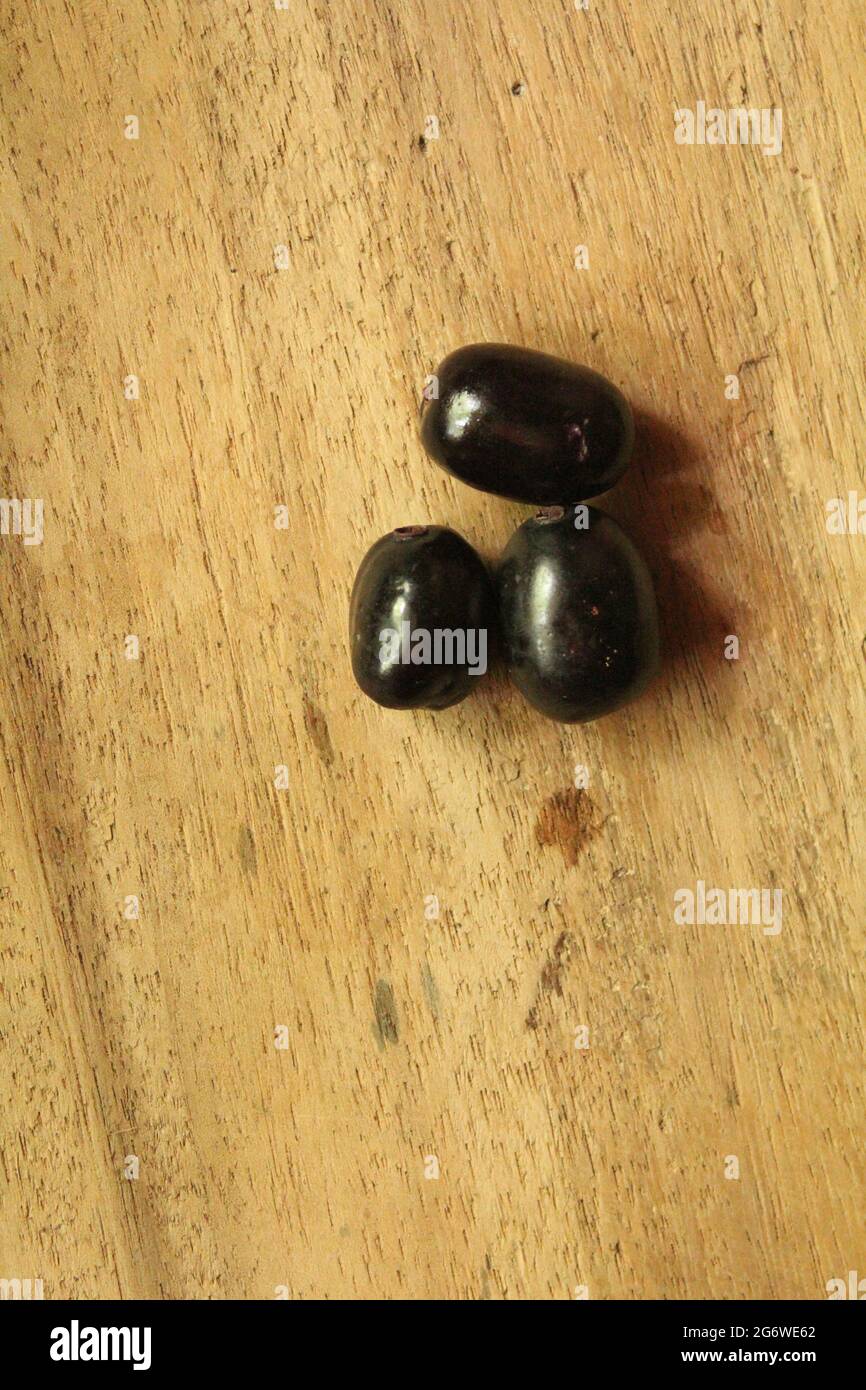 Java-Pflaumenfrüchte oder syzygium-Früchte auf isolierter Holzoberfläche, Draufsicht, blaue Beerenfrucht, neues Bild Stockfoto
