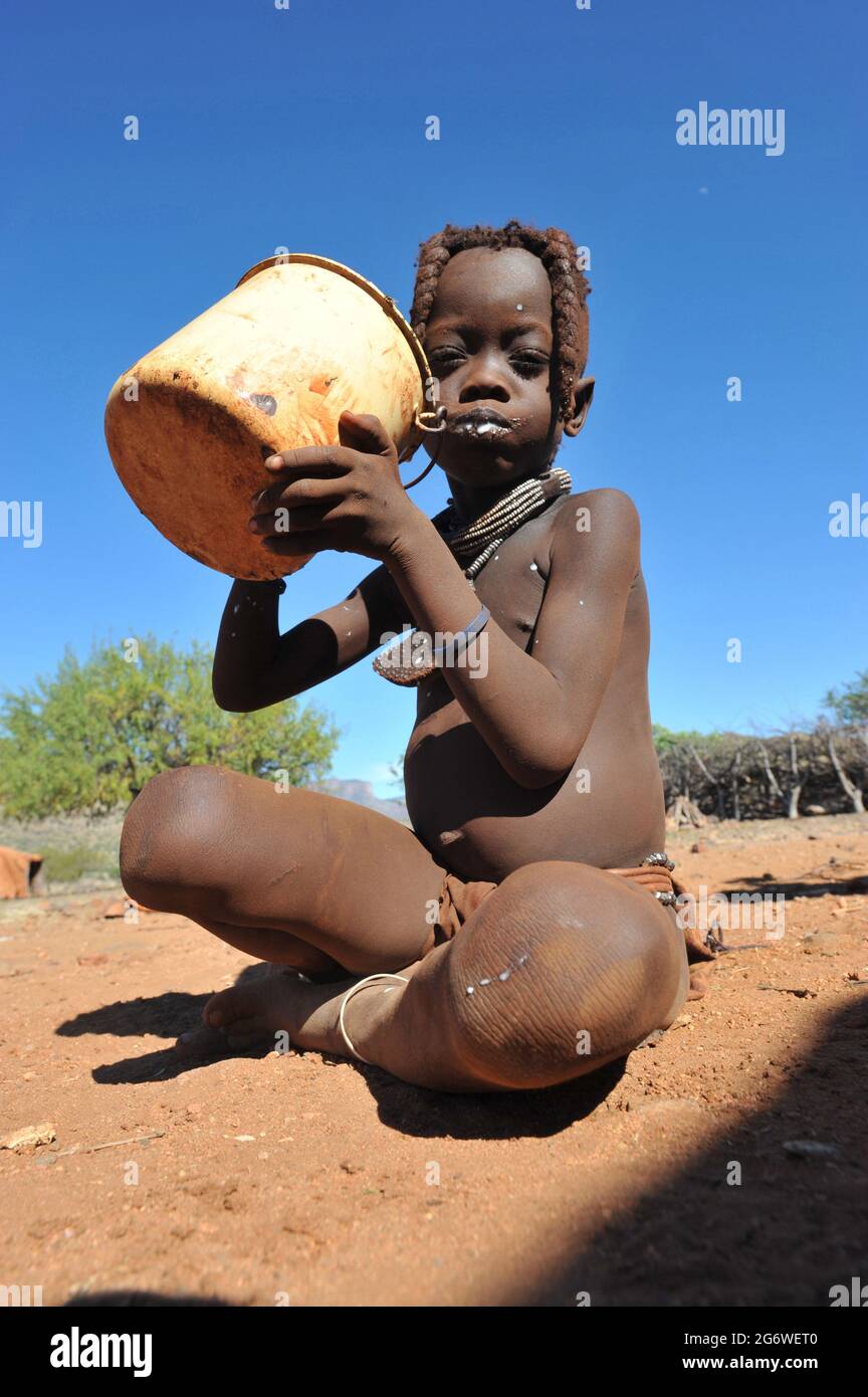 NAMIBIA. JUNGES HIMBA-MÄDCHEN, DAS MILCH TRINKT. HAUPTQUELLE VON PROTEINEN, DIE MILCH WIRD FRISCH GETRUNKEN ODER IN KALABASCHEN EINGEKRÜPPT. Stockfoto