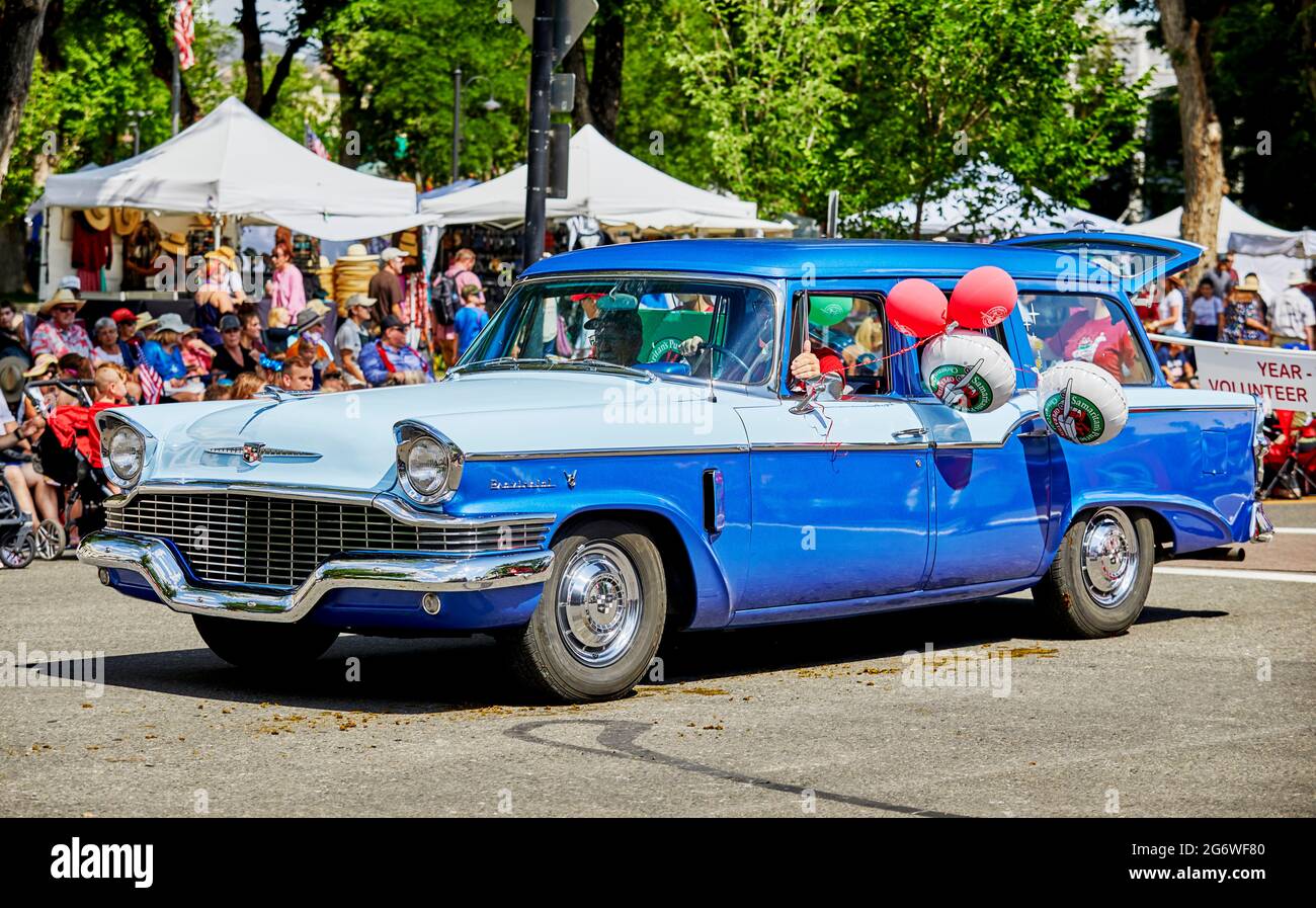 Prescott, Arizona, USA - 3. Juli 2021: Mann fährt bei der Parade am 4. Juli mit einem antiken blauen zweifarbigen Auto mit Ballons aus dem Fenster Stockfoto