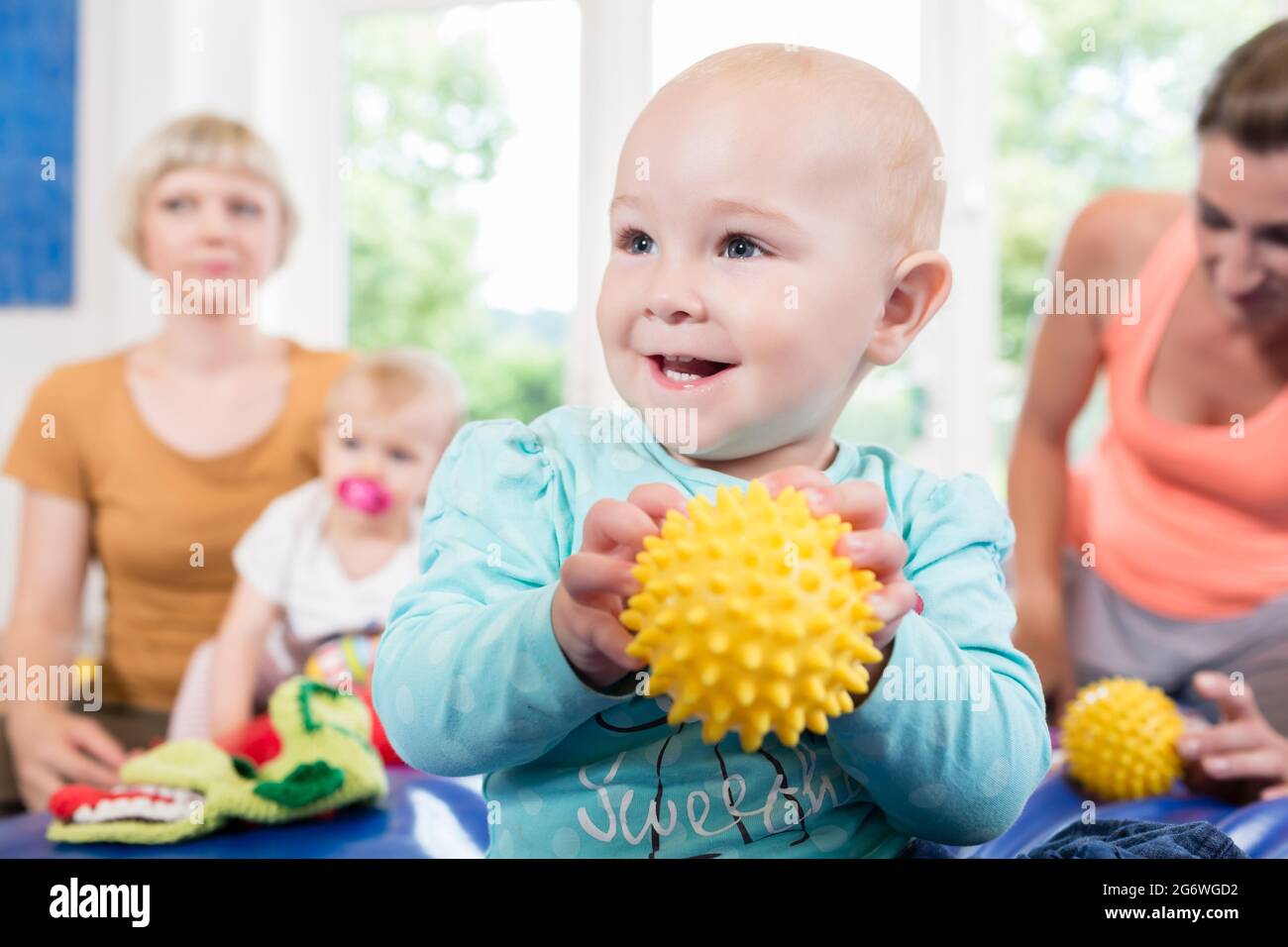 Babys mit Schnuller in der Kleinkindgruppe spielen mit Spielzeug im Babykurs Stockfoto