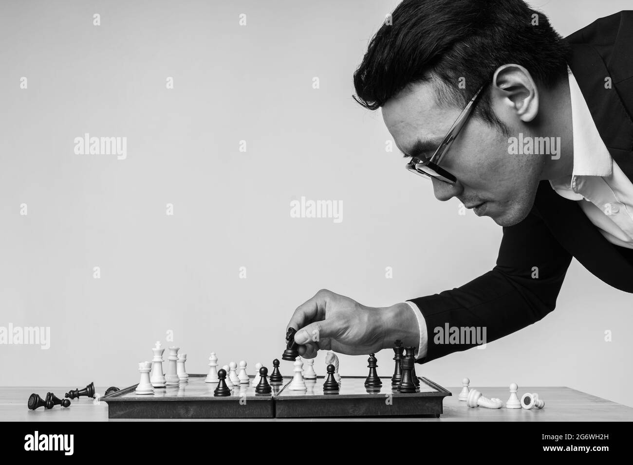 Der asiatische Geschäftsmann denkt über seinen nächsten Schritt auf dem Schachbrett nach Stockfoto