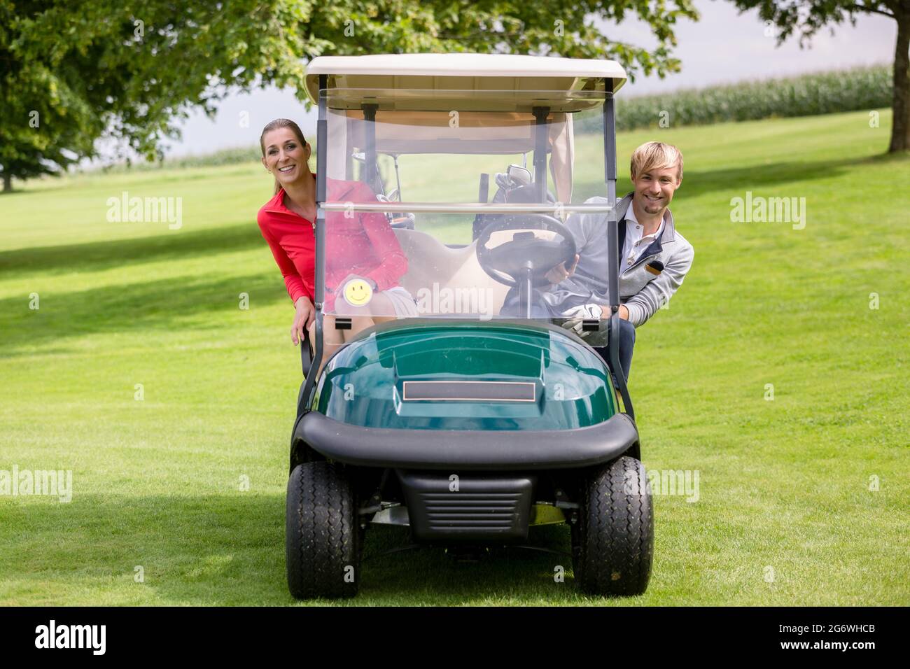 Portrait von glückliches junges Paar in der Golfkarre sitzen peeking Stockfoto