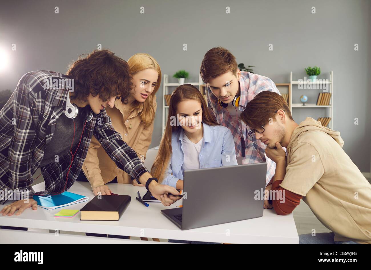 Eine Gruppe von Studenten, die an einem gemeinsamen Hochschulprojekt arbeiten und an einem Laptop im Klassenzimmer sitzen. Stockfoto