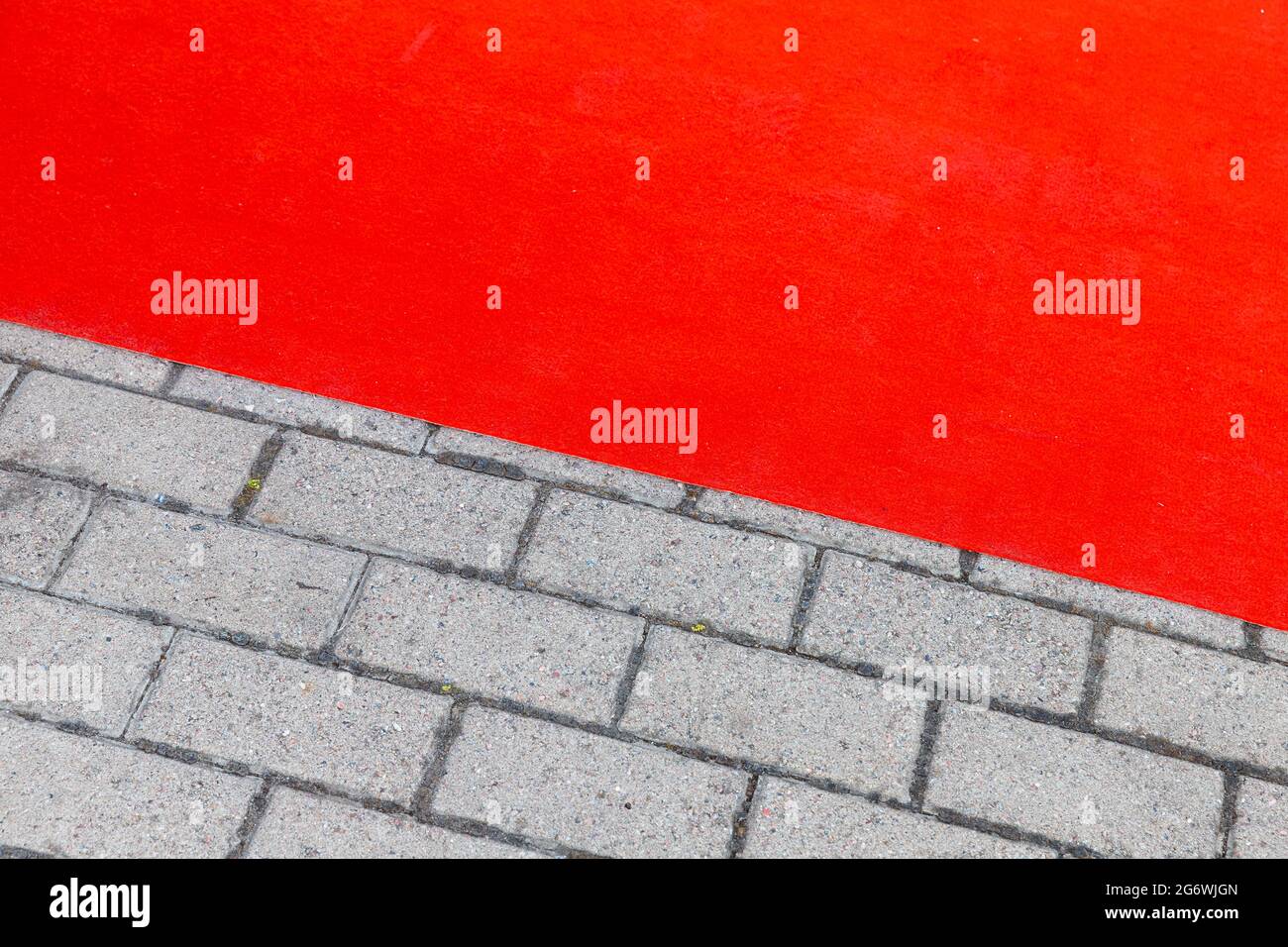 Roter Teppich legt sich über graue gepflasterte Straße, Hintergrund Foto Textur Stockfoto
