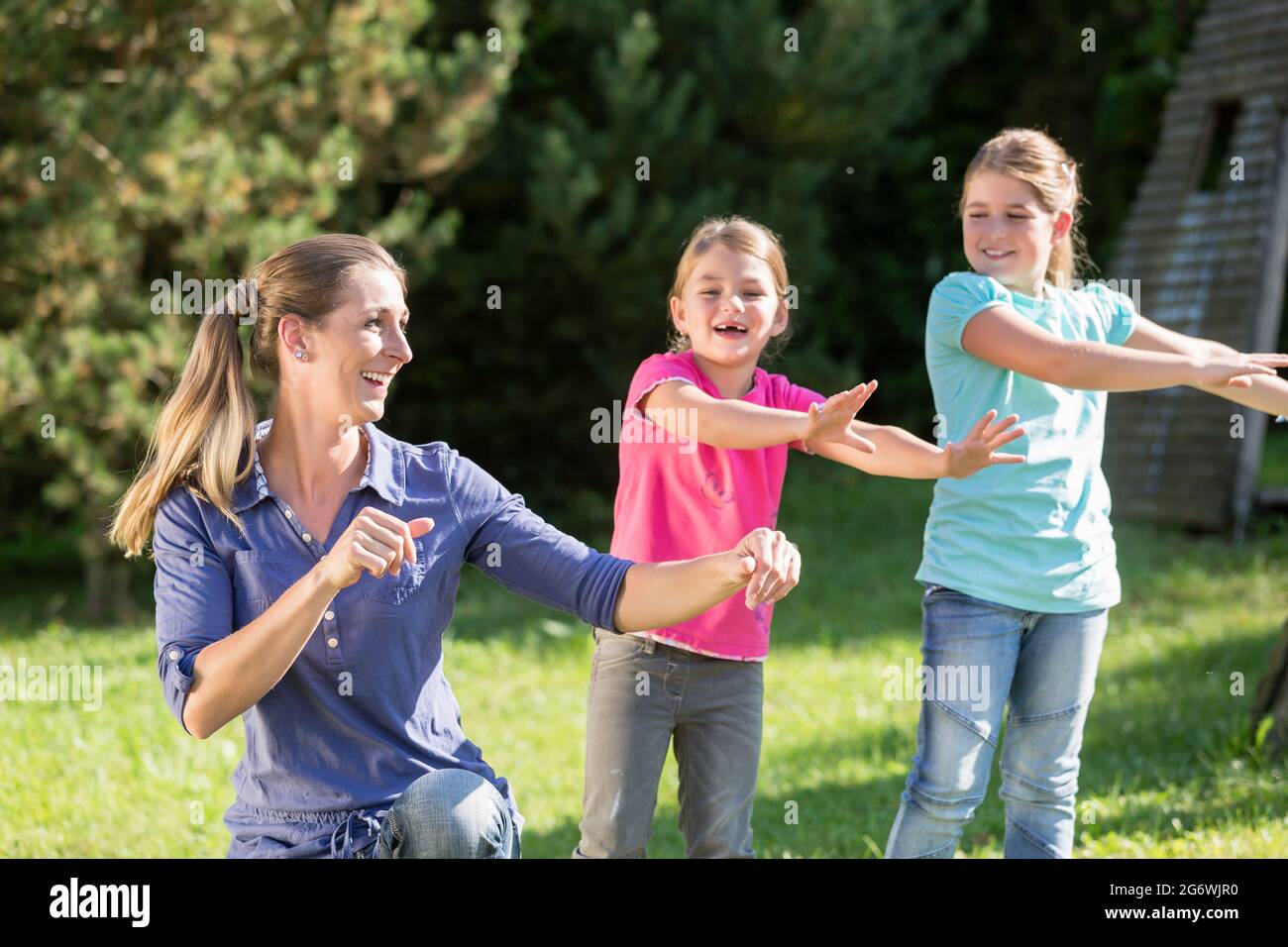 Glückliche Mutter mit Kindern Töchter tun Tanz Übung im Freien Stockfoto
