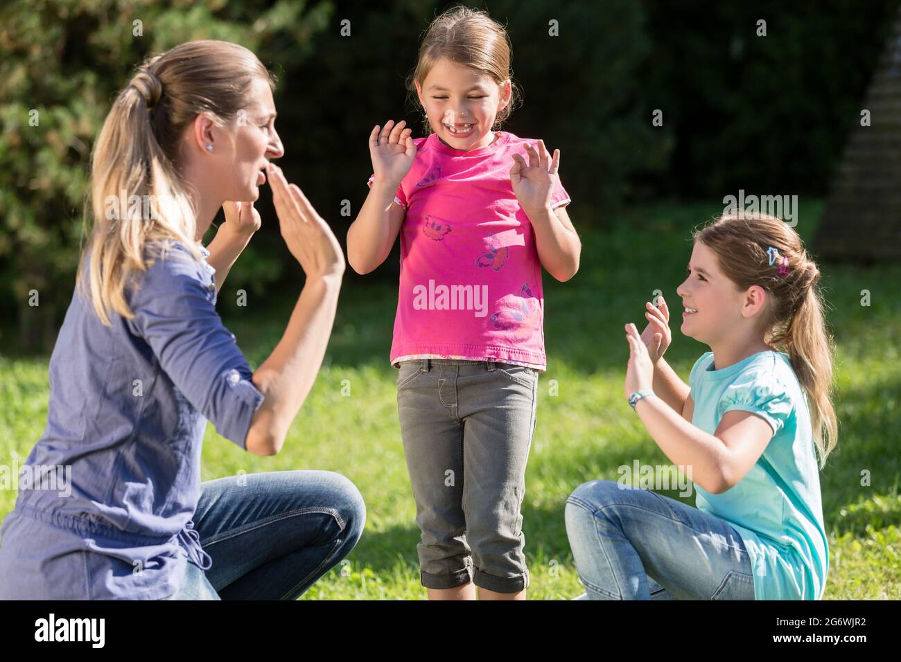 Glückliche Mutter mit Kindern Töchter tun Tanz Übung im Freien Stockfoto