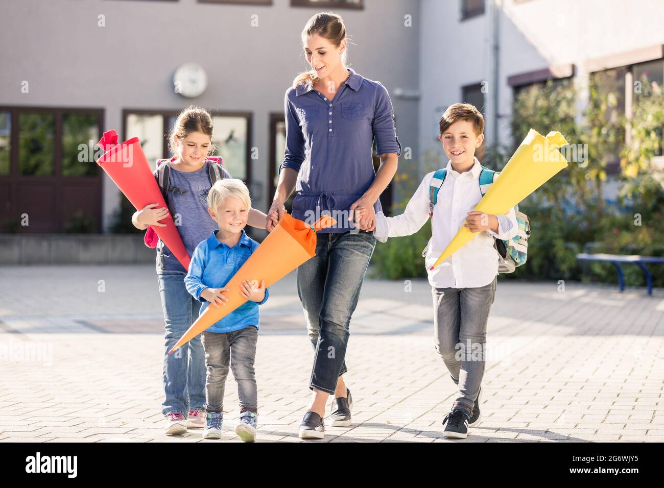 Mutter und Kinder mit Papiertrichtern für Süßigkeiten nach dem ersten Schultag Stockfoto