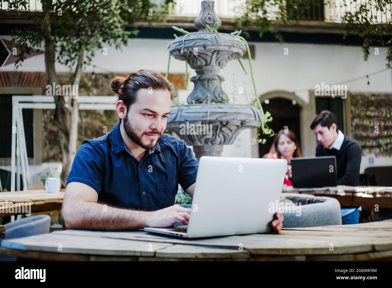 Junger lateinischer College-Mann, der Computer benutzt, während er im College-Hof sitzt Stockfoto