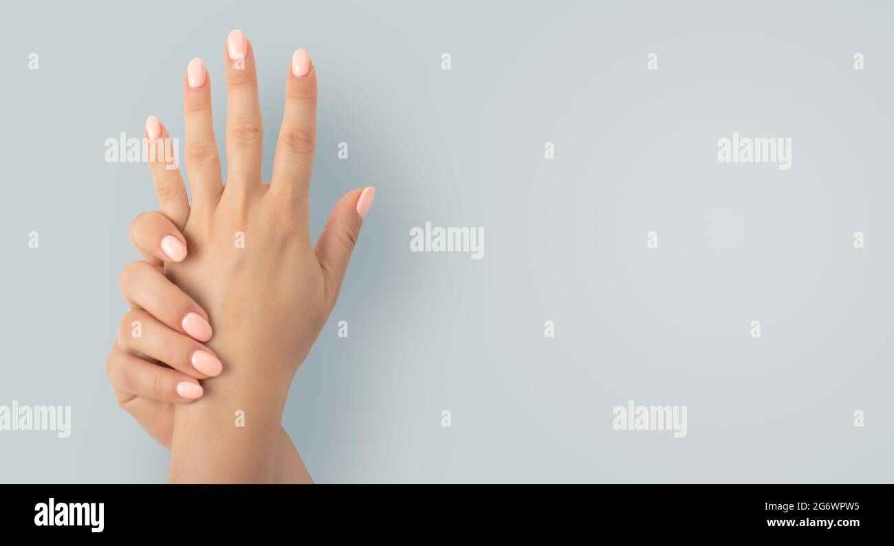 Schöne weibliche Hände mit stilvollem Maniküre-Gel-Nagellack auf grauem Hintergrund. Nahaufnahme der Frau mit schönen Händen auf grauem Hintergrund, Raum Stockfoto