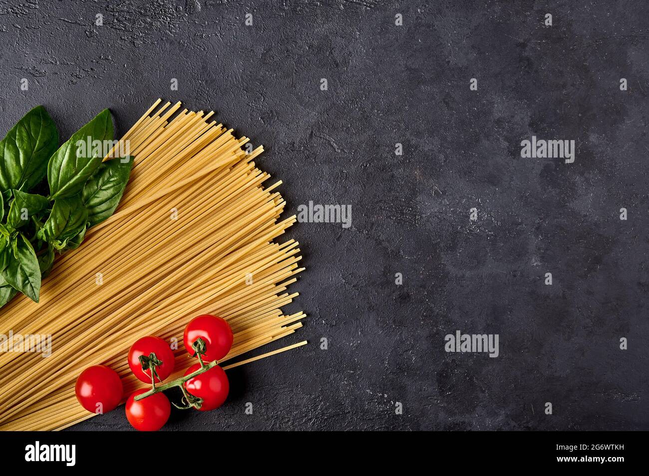 Italienische Spaghetti mit Basilikumblättern und Tomaten auf dunklem strukturiertem Hintergrund, angeordnet in den Farben der italienischen Flagge. Draufsicht. Speicherplatz kopieren Stockfoto