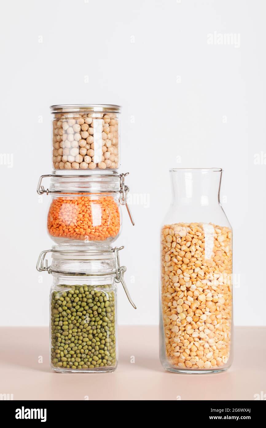 Vegane Proteinquelle. Erbsen, Kichererbsen, Linsen, Mungn in Gläsern auf weißem und beigem Hintergrund. Gesundes vegetarisches Essen. Platz kopieren Stockfoto