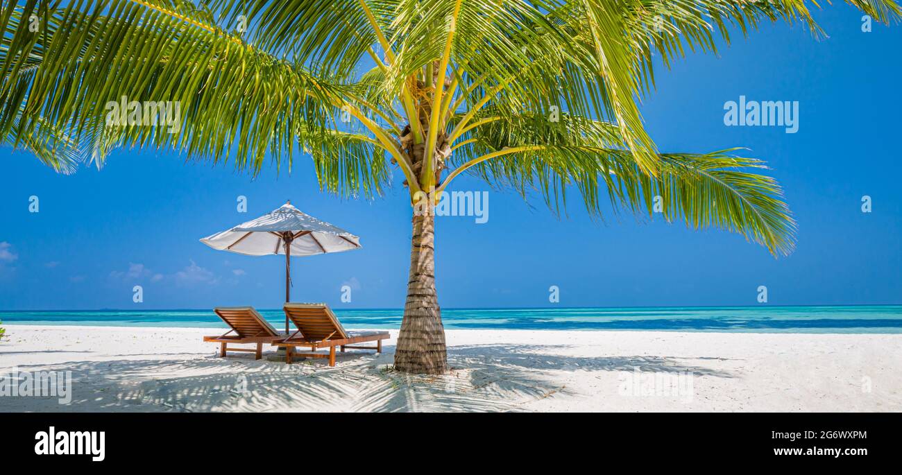 Wunderschöne tropische Insellandschaft, zwei Sonnenliegen, Liegen, Sonnenschirm unter Palmen. Weißer Sand, Meerblick mit Horizont, idyllisch blauer Himmel, Ruhe Stockfoto
