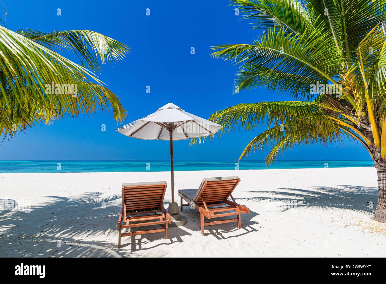 Tropische Strandnatur als Sommerlandschaft mit Liegestühlen und Palmen und ruhiges Meer für Strandbanner. Luxuriöse Reise Urlaub Urlaubslandschaft Stockfoto