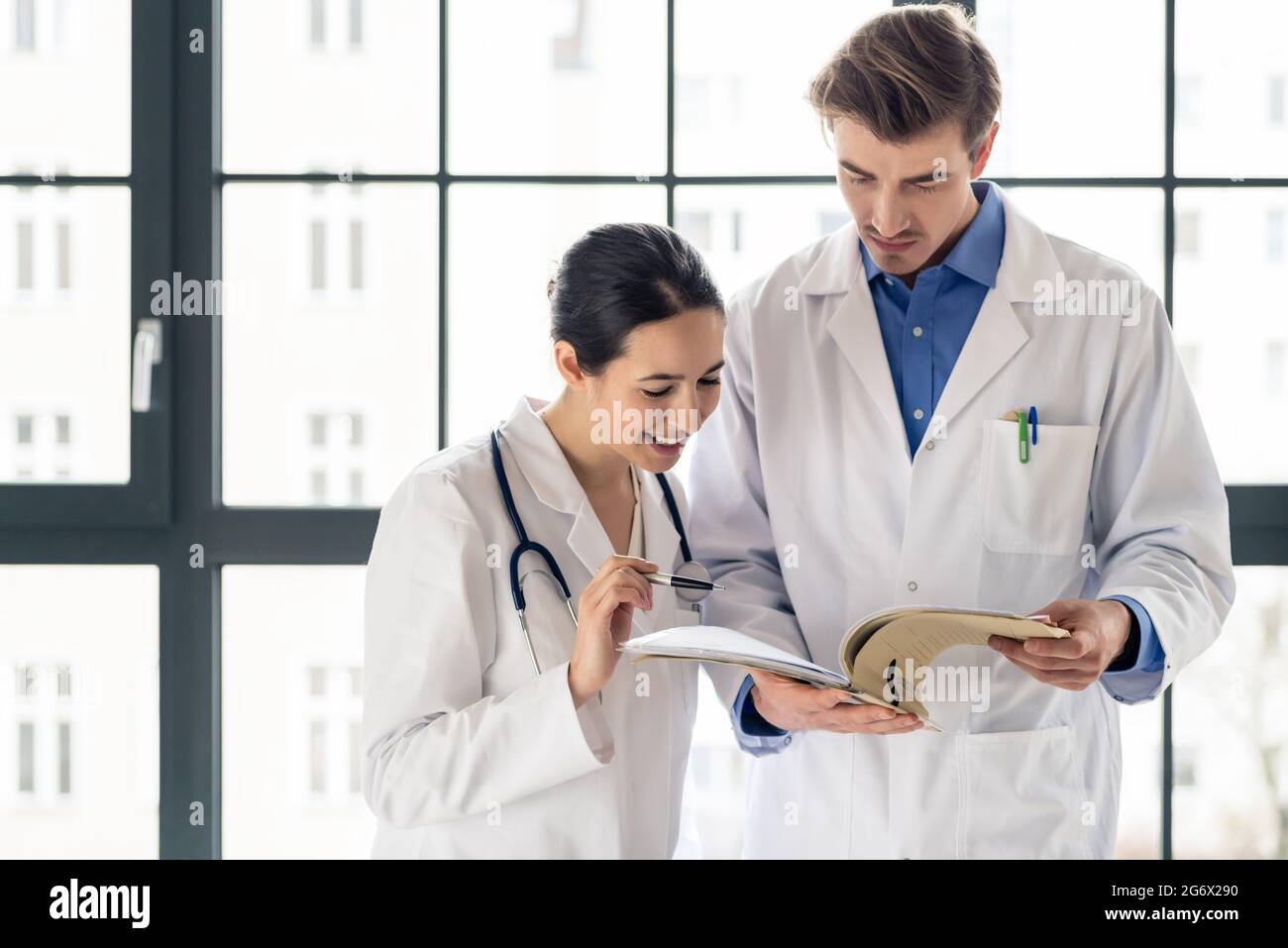 Zwei engagierte Ärzte gemeinsam Prüfen der Informationen aus der Krankenakte eines Patienten in das Innere eines modernen Krankenhaus Stockfoto