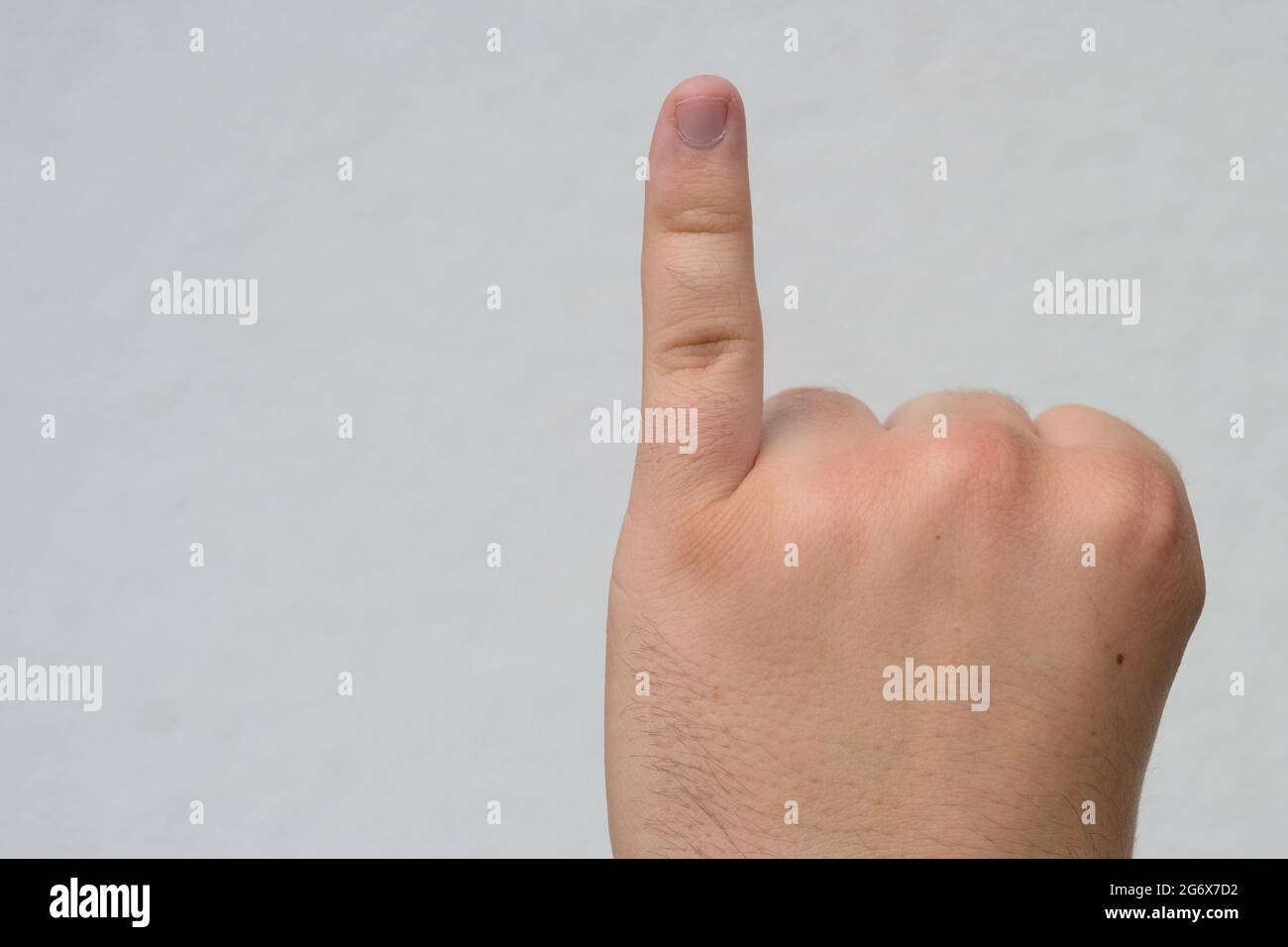 Mann, der seinen kleinen Finger oder rosafarben Finger zeigt, indem er ihn in der Nähe über Weiß mit Copyspace hebt, möglicherweise auch einen beim Zählen zeigt Stockfoto
