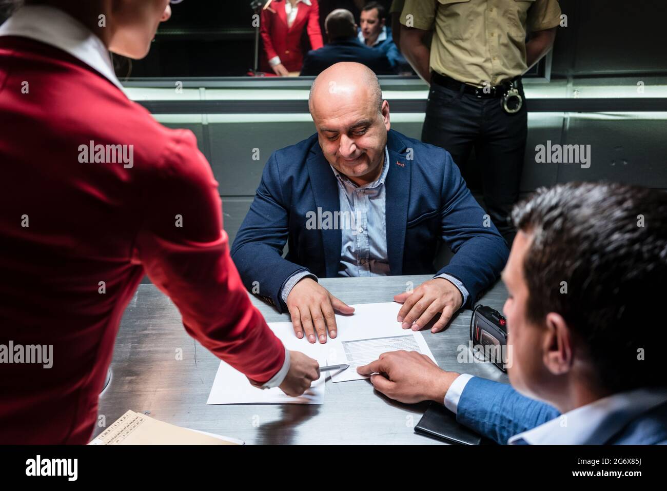 Angeklagter oder Zeuge mittleren Alters, geraten vom Anwalt, während einer strafrechtlichen Untersuchung vor dem Staatsanwalt eine offizielle Erklärung zu unterzeichnen Stockfoto