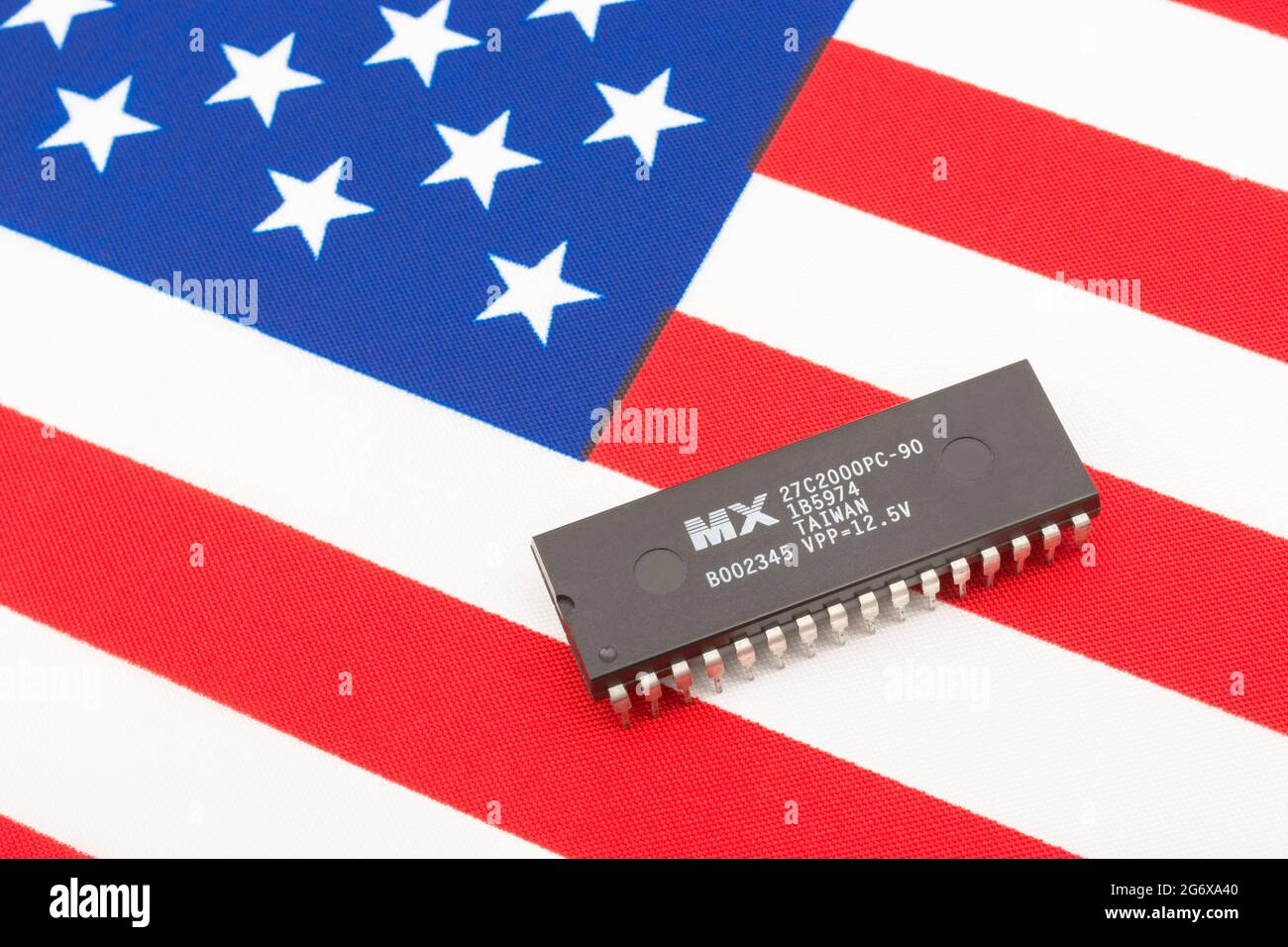 Nahaufnahme von Macronix International Integrated Circuit / EPROM Chip auf kleiner US Stars & Stripes Flagge. Für US-Halbleiterknappheit im Jahr 2021. Stockfoto
