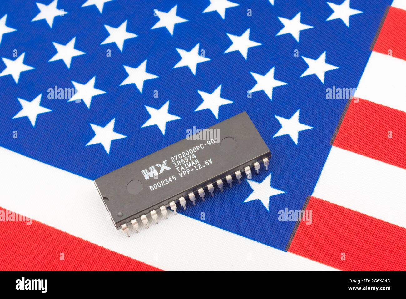 Nahaufnahme von Macronix International Integrated Circuit / EPROM Chip auf kleiner US Stars & Stripes Flagge. Für US-Halbleiterknappheit im Jahr 2021. Stockfoto