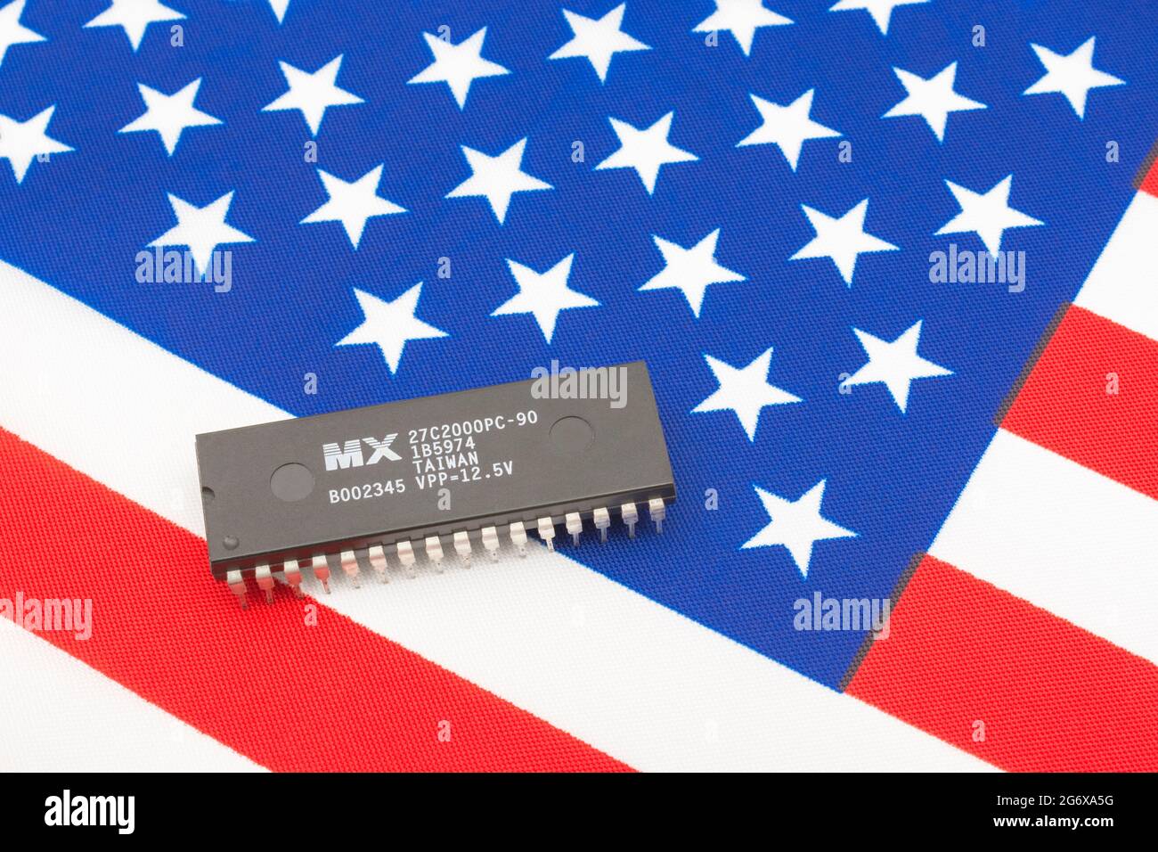 Nahaufnahme von Macronix International Integrated Circuit / EPROM Chip auf kleiner US Stars & Stripes Flagge. Für US-Halbleiterknappheit im Jahr 2021. Stockfoto