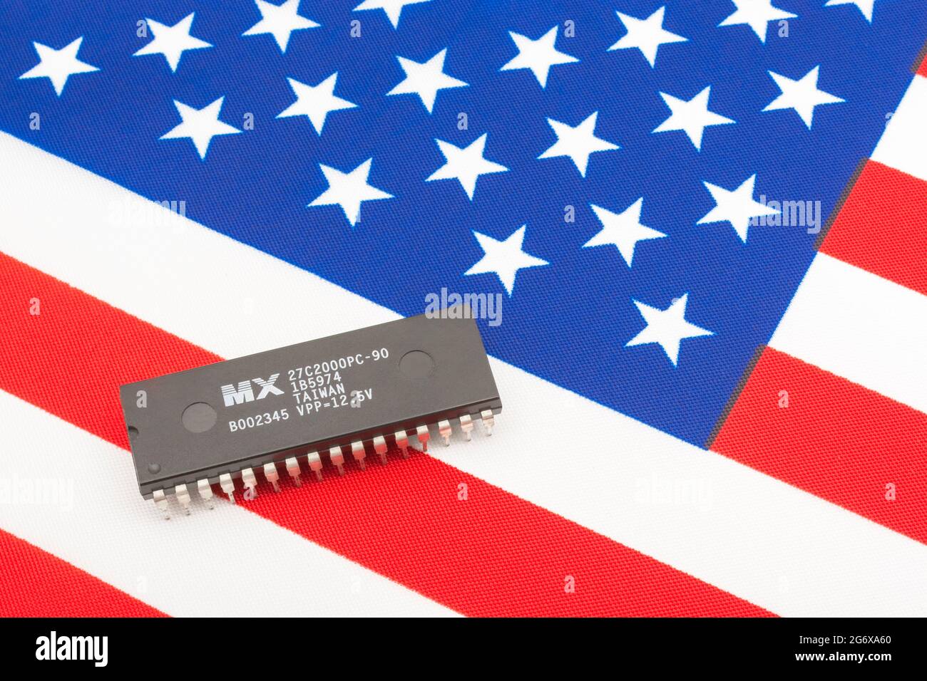 Nahaufnahme von Macronix International Integrated Circuit / EPROM Chip auf kleiner US Stars & Stripes Flagge. Für US-Halbleiterknappheit im Jahr 2021. Stockfoto