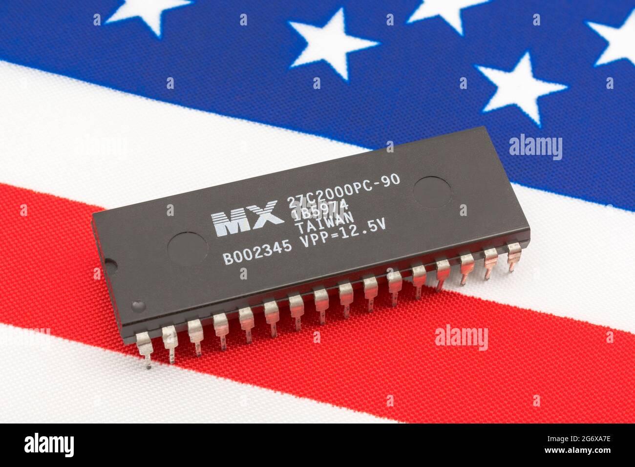 Nahaufnahme von Macronix International Integrated Circuit / EPROM Chip auf kleiner US Stars & Stripes Flagge. Für US-Halbleiterknappheit im Jahr 2021. Stockfoto