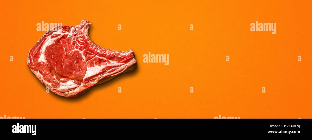 Rohes Rindfleisch Prime Rib isoliert auf orangefarbenem Hintergrund. Draufsicht. Horizontales Banner Stockfoto