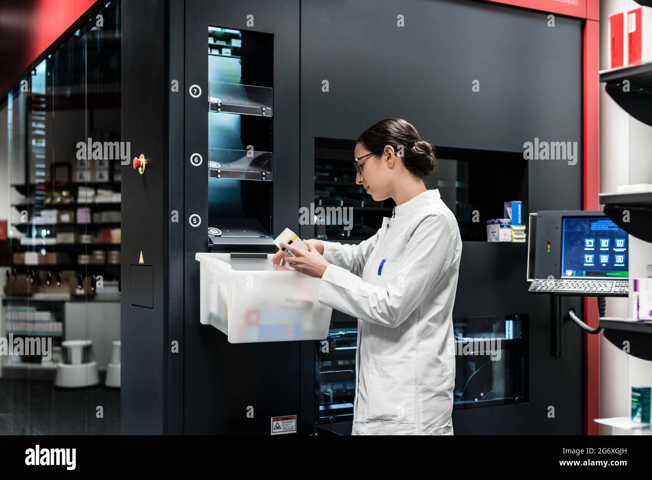 Low-angle Rückansicht eines erfahrenen weiblichen Apotheker mit einem Computer während die Droge Lager verwalten in einer modernen Apotheke mit modernen Technologien Stockfoto