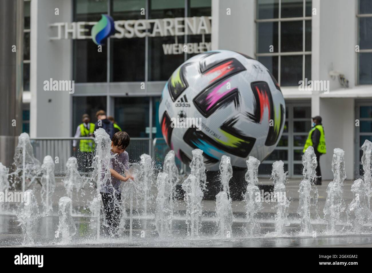 Wembley Park, Großbritannien. Juli 2021. Kinder spielen in den Springbrunnen vor der SSE Arena, wo auf dem Arena Square eine riesige Nachbildung des Adidas-Fußballs „UNIFORIA FINALE“ - der offizielle Spielball für das Finale - zu sehen ist. 60,000 Fans werden am Sonntag, den 11. Juli, im Wembley-Stadion im Wembley-Stadion in Italien beim UEFA EURO 2020-Finale spielen. Amanda Rose/Alamy Live News Stockfoto