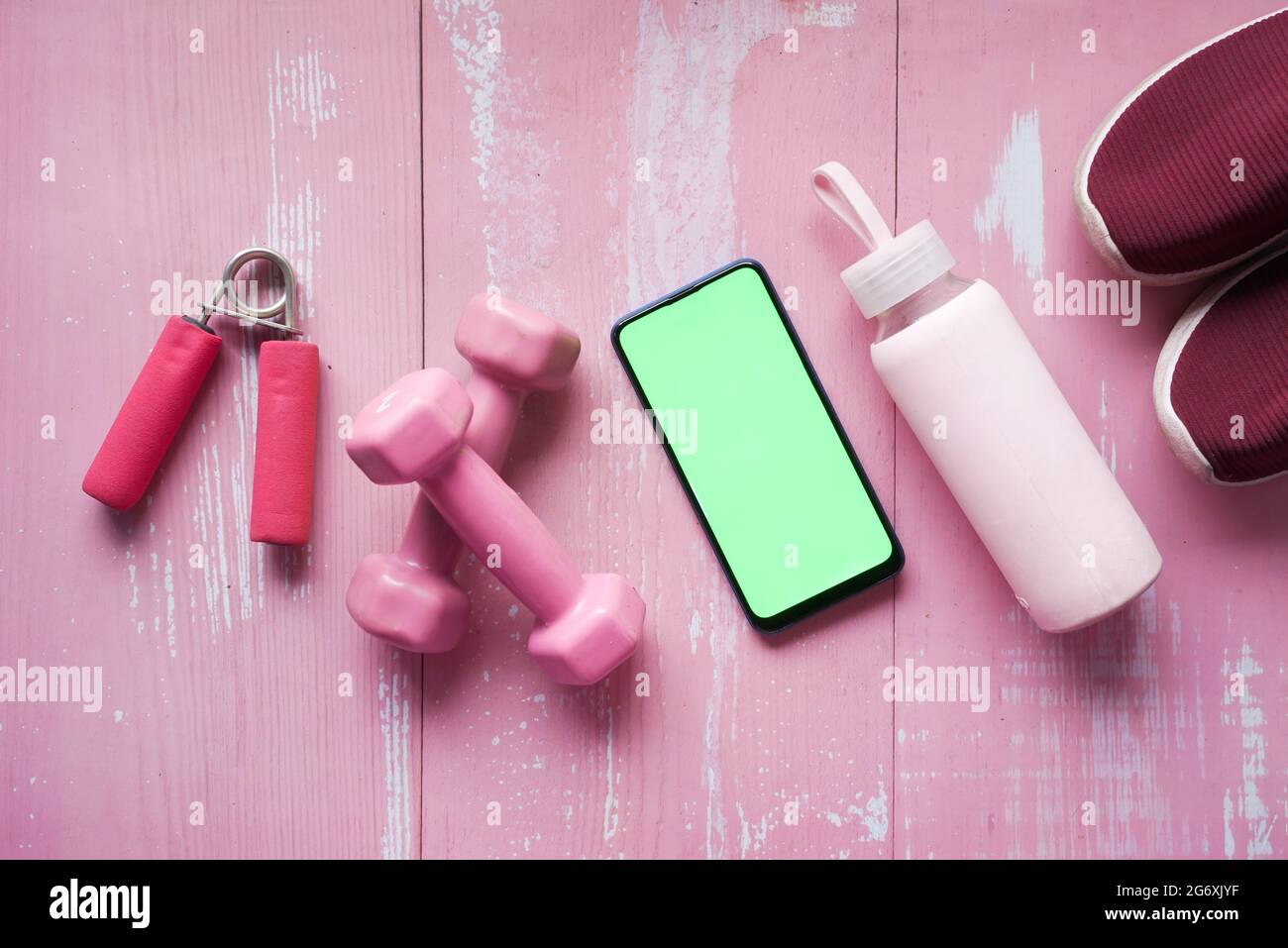 Smartphone mit Sportgeräten auf Holzboden. Stockfoto