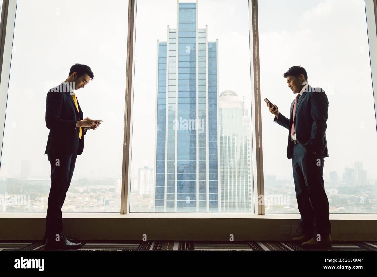 Seite vie von zwei Unternehmer mit smart phone steht in der Nähe der Fenster Stockfoto