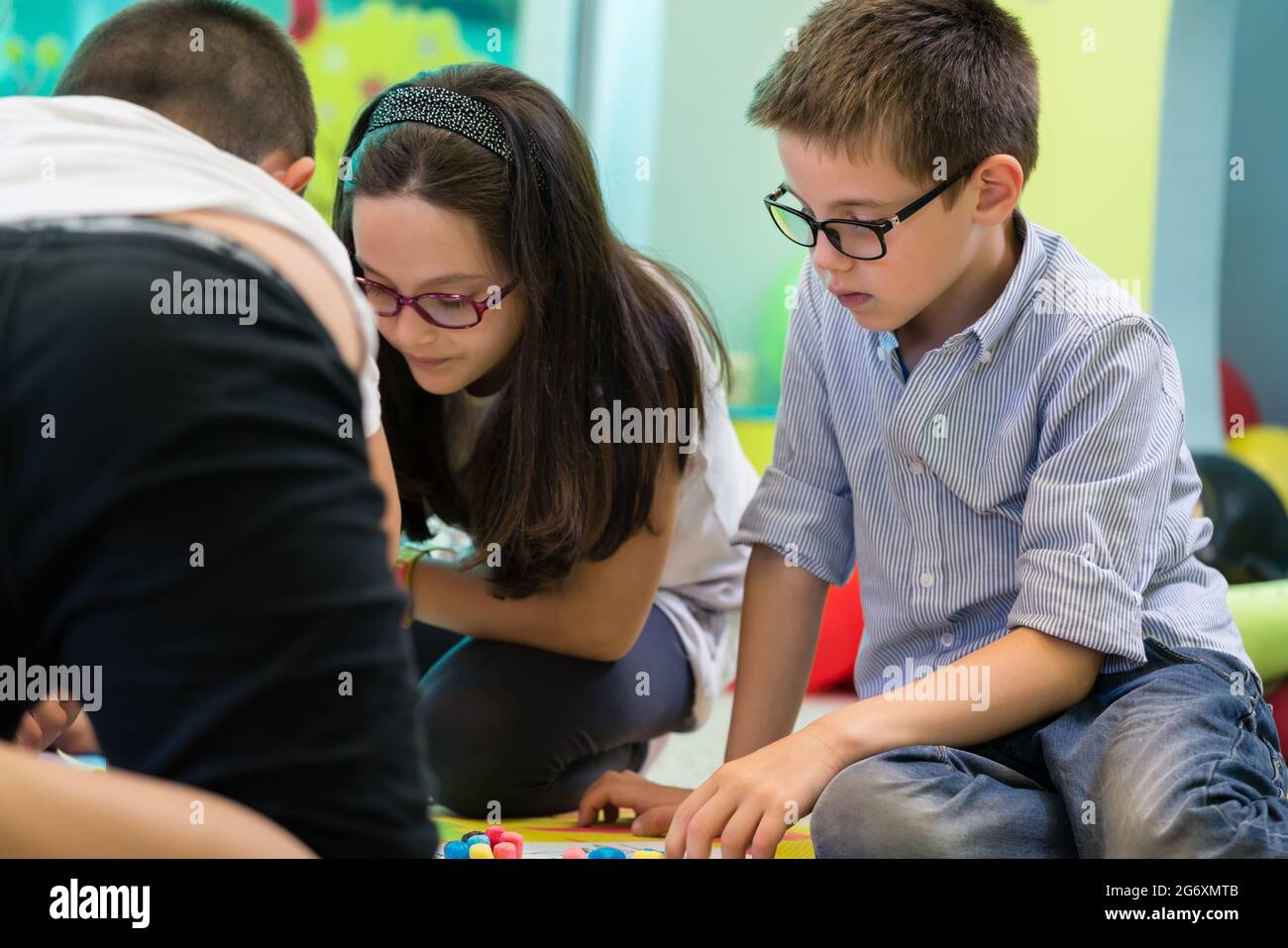 Niedliches Mädchen und Junge aus der Vorschule tragen eine Brille, während sie während einer kreativen Gruppenaktivität im Kindergarten mit Plastilin spielen Stockfoto