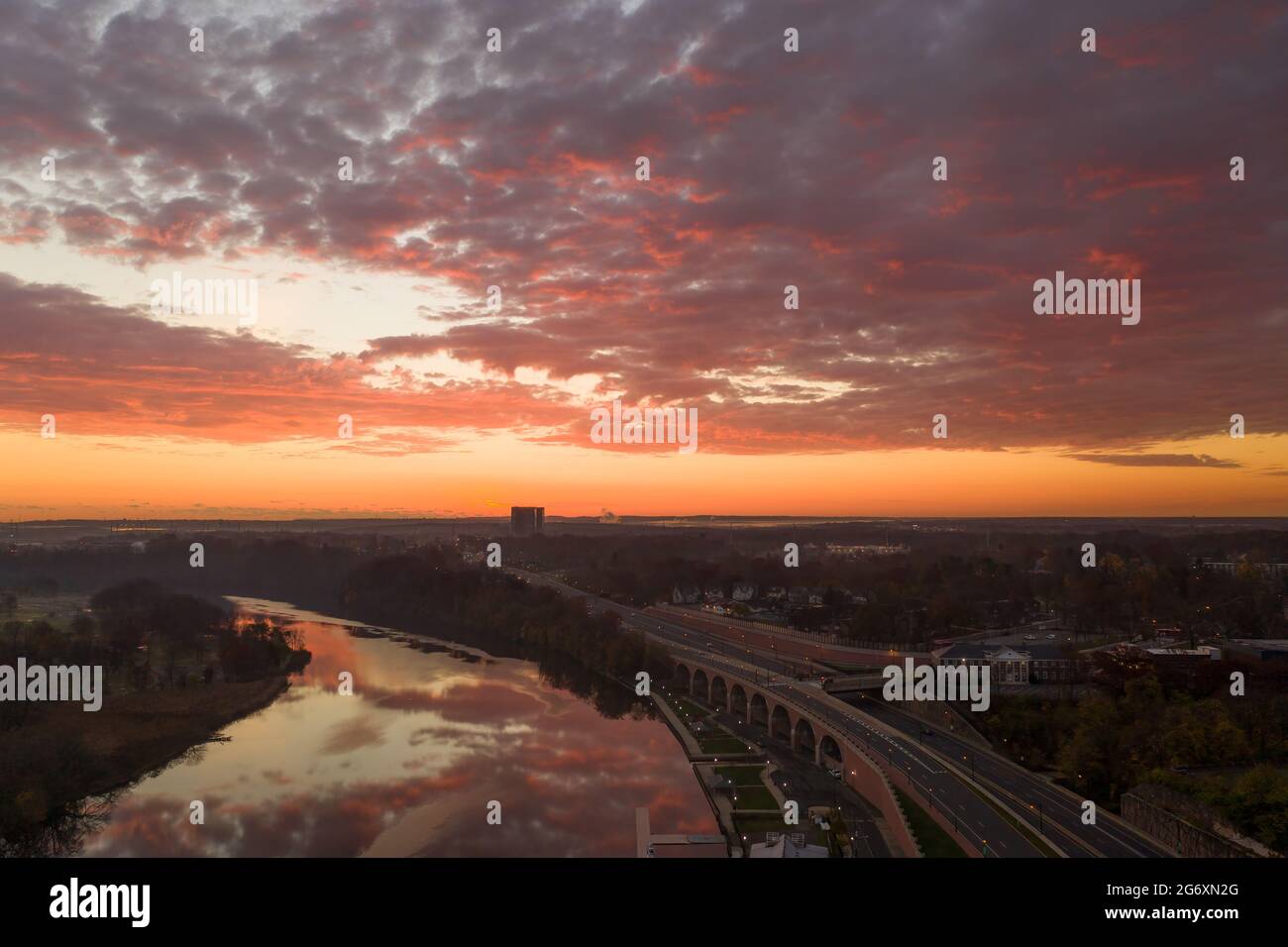 Luftaufnahme einer Stadt am Wasser am frühen Morgen mit Reflexionen aus dem bunten Himmel. Stockfoto