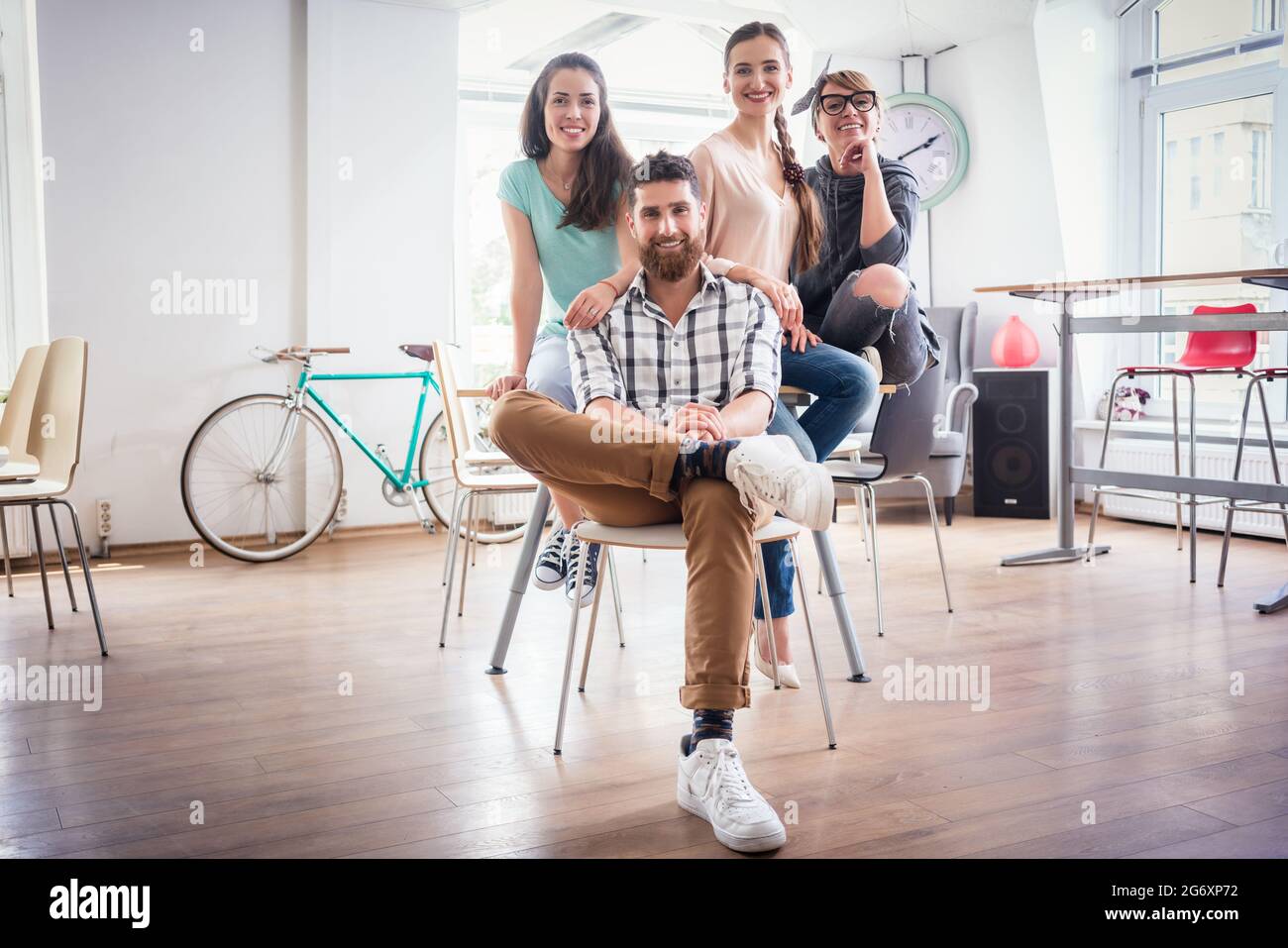 Porträt der vier Mitarbeiter lächelnd und mit Blick auf die Kamera beim Tragen cool legere Kleidung, während der Arbeit in der Shared Office Space eines modernen Hub fo Stockfoto