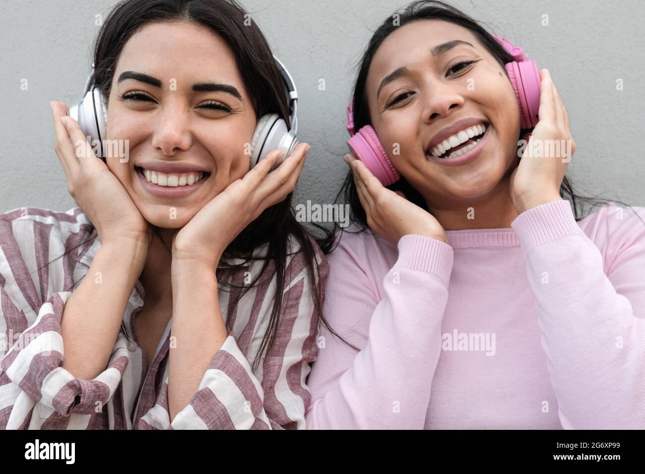 Junge fröhliche Latin-Mädchen, die Spaß haben, Musik mit kabellosen Kopfhörern im Freien zu hören Stockfoto