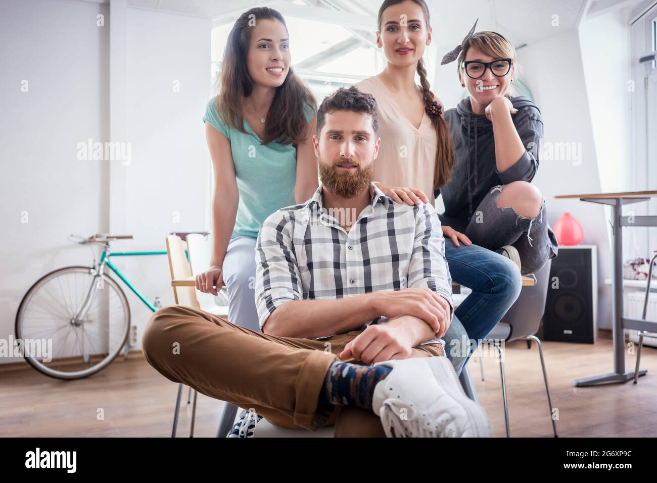 Porträt der vier Mitarbeiter lächelnd und mit Blick auf die Kamera, beim Tragen cool legere Kleidung während der Arbeit in der Shared Office Space eines modernen Hub fo Stockfoto