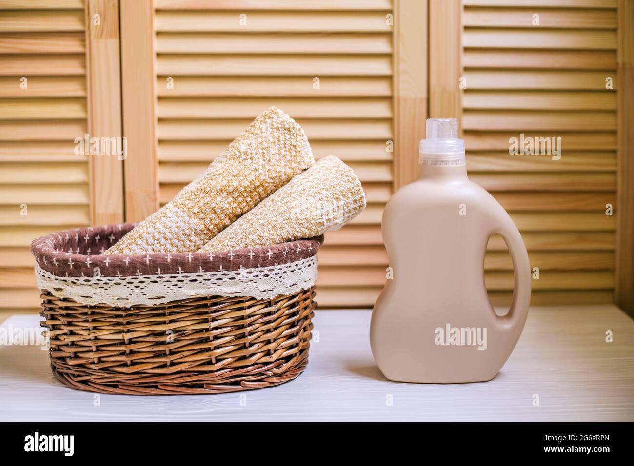 Waschmittelflasche in der Nähe eines Stapels Handtücher im Korb. Stockfoto