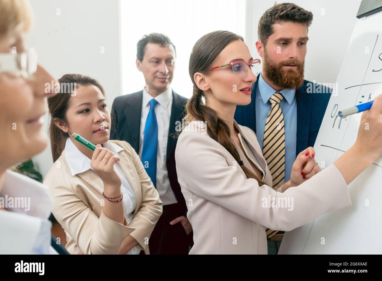 Portrait von einer kompetenten business Frau lächelnd, während die Analyse der Chancen für ein neues Projekt während einer interaktiven Besprechung mit dem Vorstand di Stockfoto