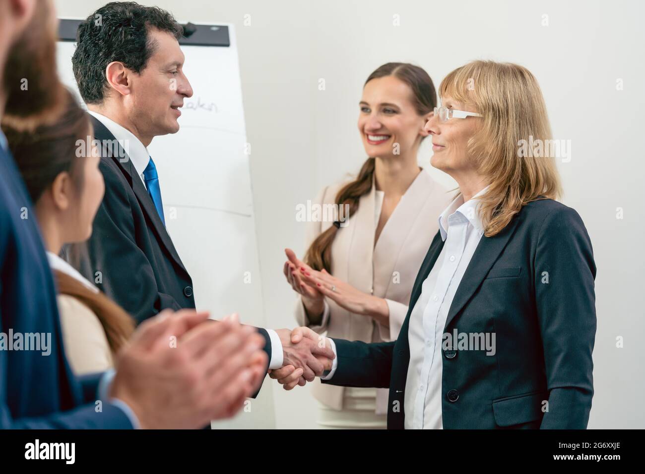 Zwei im mittleren Alter Geschäftspartner lächelnd, während die Hände schütteln als Vereinbarung nach der Sitzung im Konferenzraum eines multinationalen Unternehmens Stockfoto
