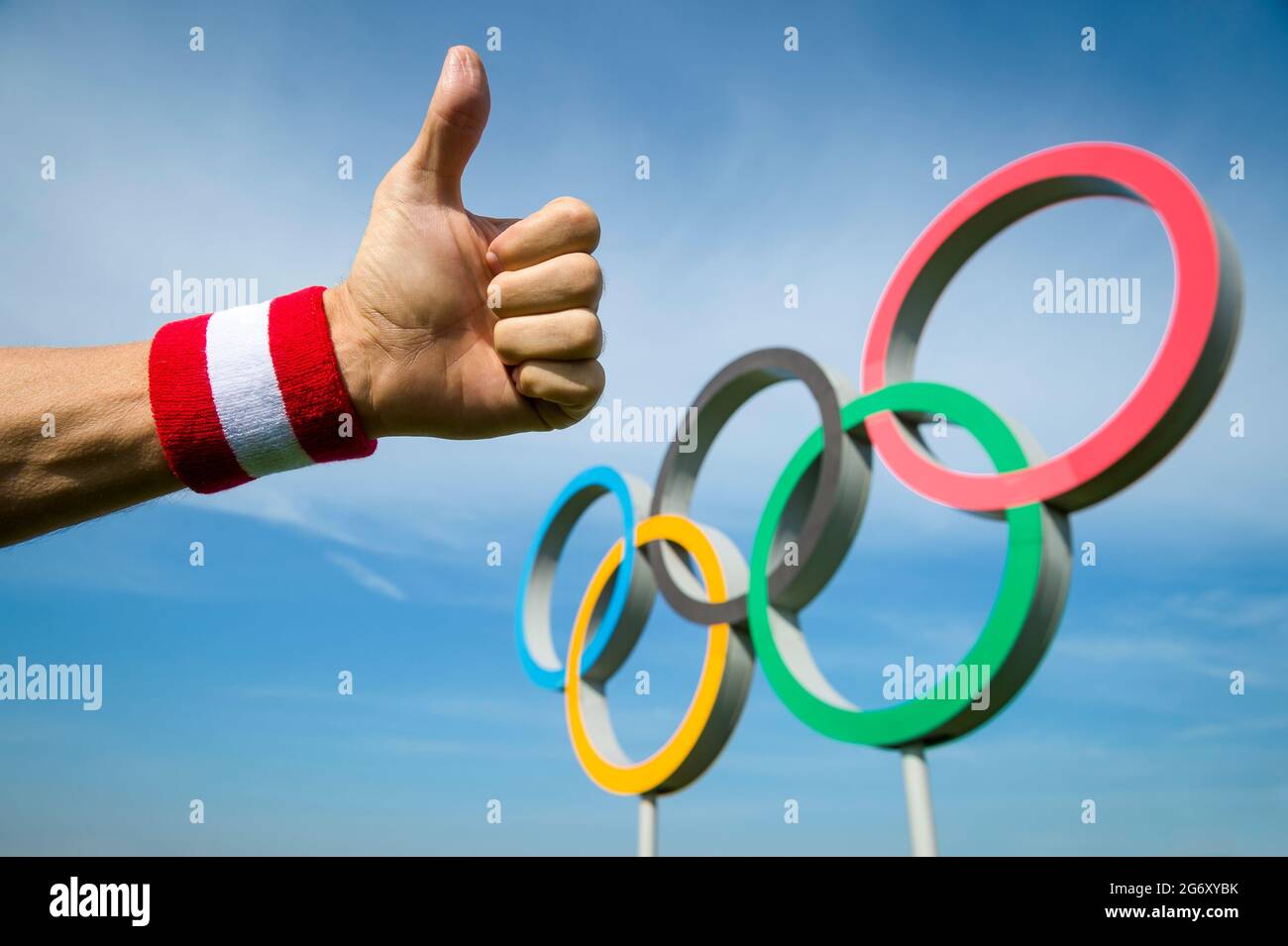 RIO DE JANEIRO - 4. MAI 2016: Die Hand des japanischen Athleten mit rot-weißem Armband zeigt sich mit Daumen nach oben vor den Olympischen Ringen, die un stehen Stockfoto